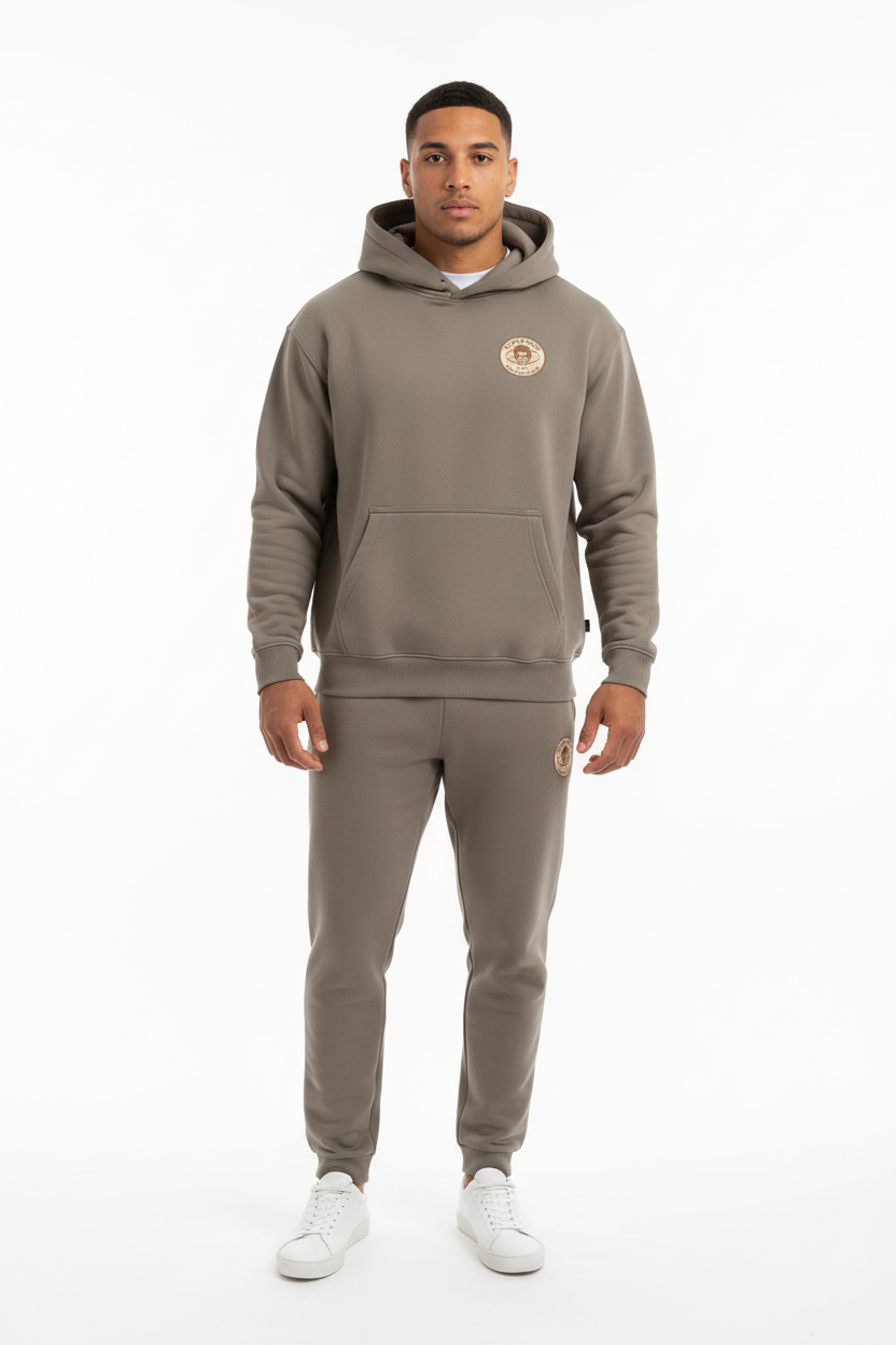 Full body front view of male model wearing grey Ten Attire Rugby skull badge hoodie